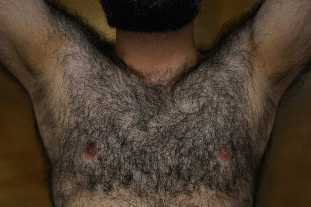 Man laying with arms behind his head and hairy chest from the bear community